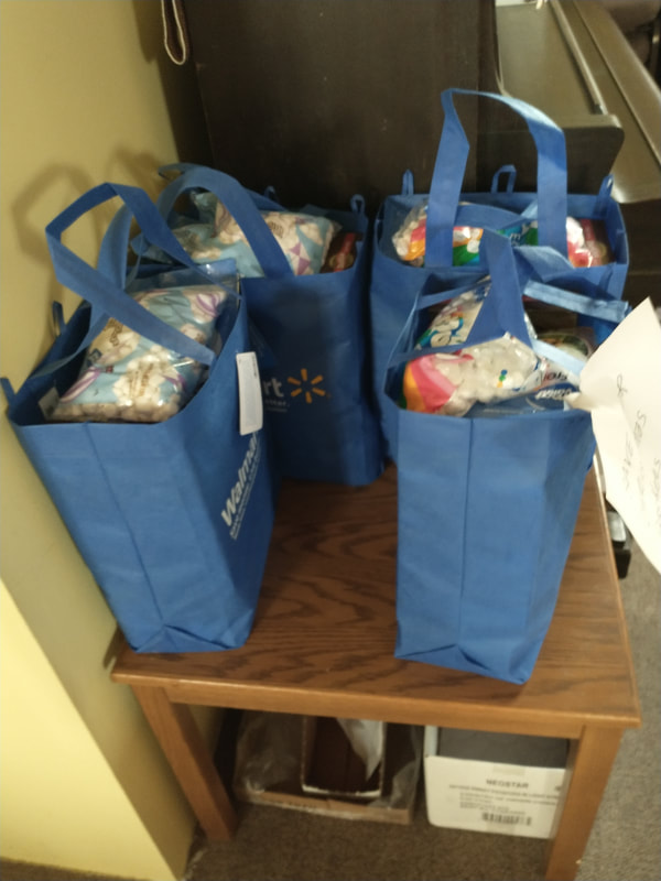 Blue reusable grocery bags filled with holiday meal kit items